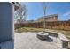 Backyard with a stone fire pit and seating area, surrounded by grass, a fence and trees at 10037 Idalia St, Commerce City, CO 80022