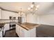Bright kitchen with white cabinets, stainless steel appliances, large center island, and dark wood floors at 10037 Idalia St, Commerce City, CO 80022