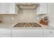 Gourmet kitchen features a stainless steel gas cooktop and gray tile backsplash at 13353 Amber Sky St, Parker, CO 80134