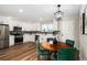 Bright kitchen with stainless appliances, white cabinets, modern backsplash and eat-in space with wood table and velvet chairs at 5304 Granby St, Denver, CO 80239