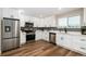 Kitchen featuring stainless steel appliances, white cabinets, subway tile backsplash, and wood-look floors at 5304 Granby St, Denver, CO 80239