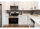 Modern kitchen with stainless steel appliances, white cabinets, gray subway tile backsplash and white quartz countertops at 5304 Granby St, Denver, CO 80239