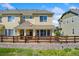 Charming tan two-story townhome with a covered porch and brick accents, complemented by a rustic wooden fence at 16212 E Geddes Ln # 11, Aurora, CO 80016