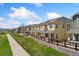 A row of two-story tan townhomes with well-manicured lawns and sidewalks, showcasing a tranquil community setting at 16212 E Geddes Ln # 11, Aurora, CO 80016
