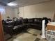 Finished basement with a large leather sectional couch and concrete floors at 7488 Quivas St, Denver, CO 80221