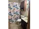 Cozy bathroom with a floral shower curtain, tiled floor, and wooden vanity at 7488 Quivas St, Denver, CO 80221