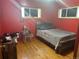 Red bedroom with hardwood floors, a modern bedframe, and two windows providing natural light at 7488 Quivas St, Denver, CO 80221