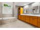 Bathroom with light wood cabinetry, soaking tub, tile floors, and large mirrors at 10293 E Sheri Ln, Englewood, CO 80111