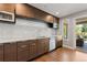 Well-equipped kitchen featuring wood cabinets, stainless steel appliances, tile backsplash, and sliding glass doors to the patio at 10293 E Sheri Ln, Englewood, CO 80111