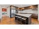 Contemporary kitchen featuring center island, wood cabinets, stainless steel appliances, and bar seating with a view to laundry area at 10293 E Sheri Ln, Englewood, CO 80111