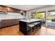 Gourmet kitchen with center island, bar seating, modern cabinetry, stainless steel appliances, and sliding glass doors to outdoor patio at 10293 E Sheri Ln, Englewood, CO 80111