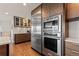 Modern kitchen with stainless steel appliances, wood cabinets, center island, and nearby coffee bar area at 10293 E Sheri Ln, Englewood, CO 80111