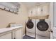 Laundry room with white cabinets, a folding rack and modern washer and dryer units at 8216 S Krameria Way, Centennial, CO 80112