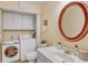 Bright bathroom with laundry area, vanity, toilet, and large, decorative circular mirror at 7040 E Girard Ave # 406, Denver, CO 80224