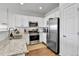 Bright kitchen features stainless steel appliances, granite countertops, and white cabinets at 6459 N Dunkirk St, Denver, CO 80249