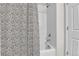 Shower with white tile, silver fixtures and a black and white patterned shower curtain at 6459 N Dunkirk St, Denver, CO 80249