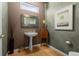 Stylish powder room with a pedestal sink, decorative mirror, and hardwood flooring at 10524 Serengeti Dr, Lone Tree, CO 80124