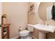 Cozy half bath featuring a pedestal sink, oval mirror, and decorative wall accents at 27235 E Lakeview Pl, Aurora, CO 80016