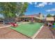 Spacious backyard featuring artificial turf, a patio area, a playhouse, and comfortable seating under mature trees at 1817 S Perry Way, Denver, CO 80219