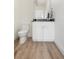 A well-lit half-bath with wood-look flooring, a white vanity, and modern fixtures at 2012 W 46Th Ave, Denver, CO 80211