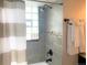 Bathroom featuring tiled shower with glass block window, neutral decor and towel rack at 2200 W Moffat Pl, Denver, CO 80221