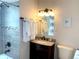 Well-lit bathroom with updated vanity, decorative mirror, and tiled shower at 2200 W Moffat Pl, Denver, CO 80221