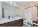 Well-lit bathroom with a spacious vanity, large mirror, and shower with floral curtain at 17402 W 93Rd Pl, Arvada, CO 80007