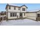 Rear exterior of a two-story home featuring white siding, gray trim, and a snowy backyard at 17402 W 93Rd Pl, Arvada, CO 80007