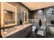 Modern bathroom featuring double sinks, illuminated mirrors, and sleek black and gray tiling at 1401 Delgany St # 409, Denver, CO 80202