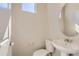 Powder room featuring a pedestal sink, toilet, and a decorative round mirror at 6993 Ipswich Ct, Castle Pines, CO 80108