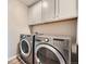 Well-equipped laundry room featuring a modern washer and dryer set with white cabinets above at 5256 Trails Edge Ln, Castle Rock, CO 80104