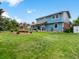 Spacious backyard view featuring a manicured lawn, two-story blue home, and mature trees at 10978 Roseanna Dr, Northglenn, CO 80234