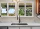 Close-up of stainless steel kitchen sink with gooseneck faucet and white cabinets, countertop, and window at 10978 Roseanna Dr, Northglenn, CO 80234