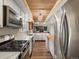 Galley kitchen featuring stainless steel appliances, white cabinets, quartz countertops, and decorative ceiling lighting at 10978 Roseanna Dr, Northglenn, CO 80234