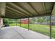 View of the back patio with a large grassy yard and shed beyond the covered area at 2280 Sherrelwood Dr, Denver, CO 80221