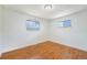 Bright bedroom with hardwood floors, white walls, and two windows for ample natural light at 2280 Sherrelwood Dr, Denver, CO 80221