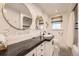 Elegant bathroom featuring black countertops, dual round mirrors, and patterned wallpaper at 3383 S Ogden St, Englewood, CO 80113