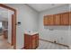 This laundry room features wooden cabinets, a deep sink, and black and white tiled flooring at 14440 Eagle Vista Dr, Littleton, CO 80127