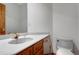 A powder room features wood cabinets, a gold faucet, a mirror, and a toilet at 14440 Eagle Vista Dr, Littleton, CO 80127