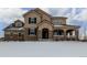 Charming two-story home featuring stone accents and a welcoming front porch and snow covered yard at 42280 Kingsmill Cir, Elizabeth, CO 80107