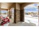 Covered porch with stone columns and red chairs, overlooking a snowy street at 42280 Kingsmill Cir, Elizabeth, CO 80107