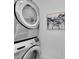 Modern laundry area with stacked washer and dryer beside a decorative painting at 2059 S Vance Way, Denver, CO 80227