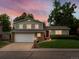 Two-story home at twilight with a red front door, attached two car garage, and a manicured front lawn at 13762 W 67Th Pl, Arvada, CO 80004