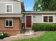 Close-up view of the red front door, brick facade, and landscaped garden in front of the two-story home at 13762 W 67Th Pl, Arvada, CO 80004