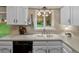 Bright kitchen features white cabinets, laminate countertops, a stainless steel faucet and a modern dishwasher at 13762 W 67Th Pl, Arvada, CO 80004