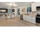 Open concept kitchen, dining, and living area featuring white cabinets, stainless appliances and modern lighting at 23222 E Orchard Pl, Aurora, CO 80015