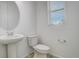 A clean half-bath with white pedestal sink and toilet next to a window at 24501 E 41St Ave, Aurora, CO 80019