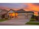 Charming home featuring a welcoming front porch and a three-car garage, set against a colorful sunset at 19468 E 65Th Pl, Aurora, CO 80019