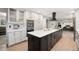 Bright kitchen featuring white cabinets, a black island, stainless steel appliances, and wood floors at 6341 E Floyd Dr, Denver, CO 80222