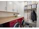 Functional laundry room featuring red washer/dryer, cabinet storage, countertop and convenient closet with shelves and hanging rod at 6341 E Floyd Dr, Denver, CO 80222